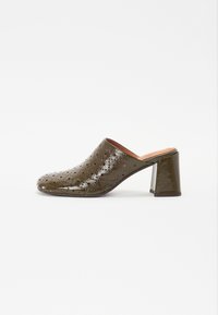 Mules à talons couleur vert olive avec texture perforée, un intérieur lisse et un talon bloc. Design élégant et moderne avec un bout arrondi.