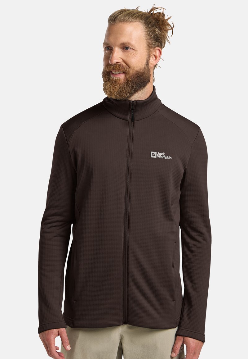 Veste en polaire brune à fermeture éclair avec un col haut, une surface texturée et des poches latérales. Présente un logo sur la poitrine gauche. Tissu durable.