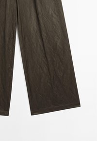 Donkerbruine, wijde broek met een gekreukt textuur. Heeft een gladde tailleband en verlengde, recht gesneden benen.
