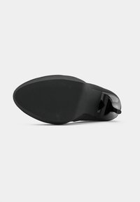 Cizmă neagră până la gleznă cu un superior din piele netedă, vârf rotunjit și toc lucios. Prezintă o talpă texturată pentru aderență și un design elegant.