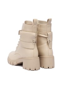 Botine din piele sintetica bej, cu toc gros, sireturi în față, buzunar lateral și detalii metalice. Talpă din cauciuc texturat.