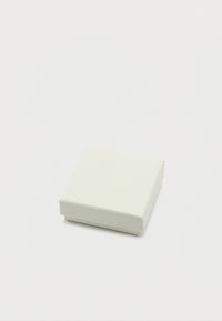 Κλειστό μικρό λευκό κουτί δώρου σε επίπεδη λευκή επιφάνεια, σε γωνιακή οπτική.