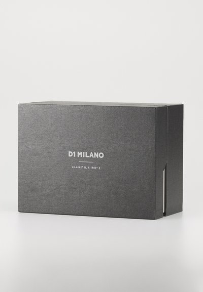 Black rectangular packaging box with a textured finish, featuring white text "D1 MILANO" and geographic coordinates on the front.