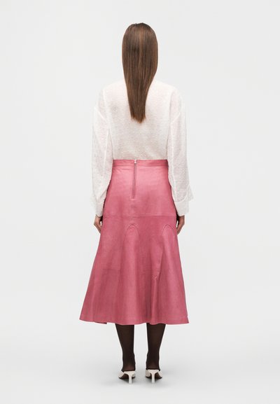 Ροζ δερμάτινη midi φούστα με φαρδιά γραμμή, με φερμουάρ στο πίσω μέρος και ραφές λεπτομέρειες. Συνδυάζεται με λευκή υφασμάτινη μπλούζα μακρυμάνικη.
