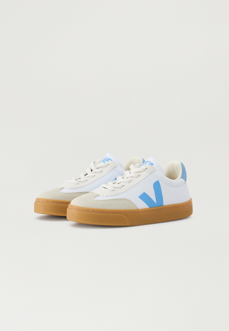 Zapatillas blancas con acentos en azul claro, puntera de ante y suela de goma. Presenta cierre de cordones y un pequeño logo en el lateral.