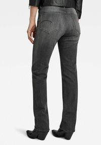 Gray denim jeans with a straight leg, visible rear pockets, and contrasting stitching, worn with black heeled boots and a leather jacket.