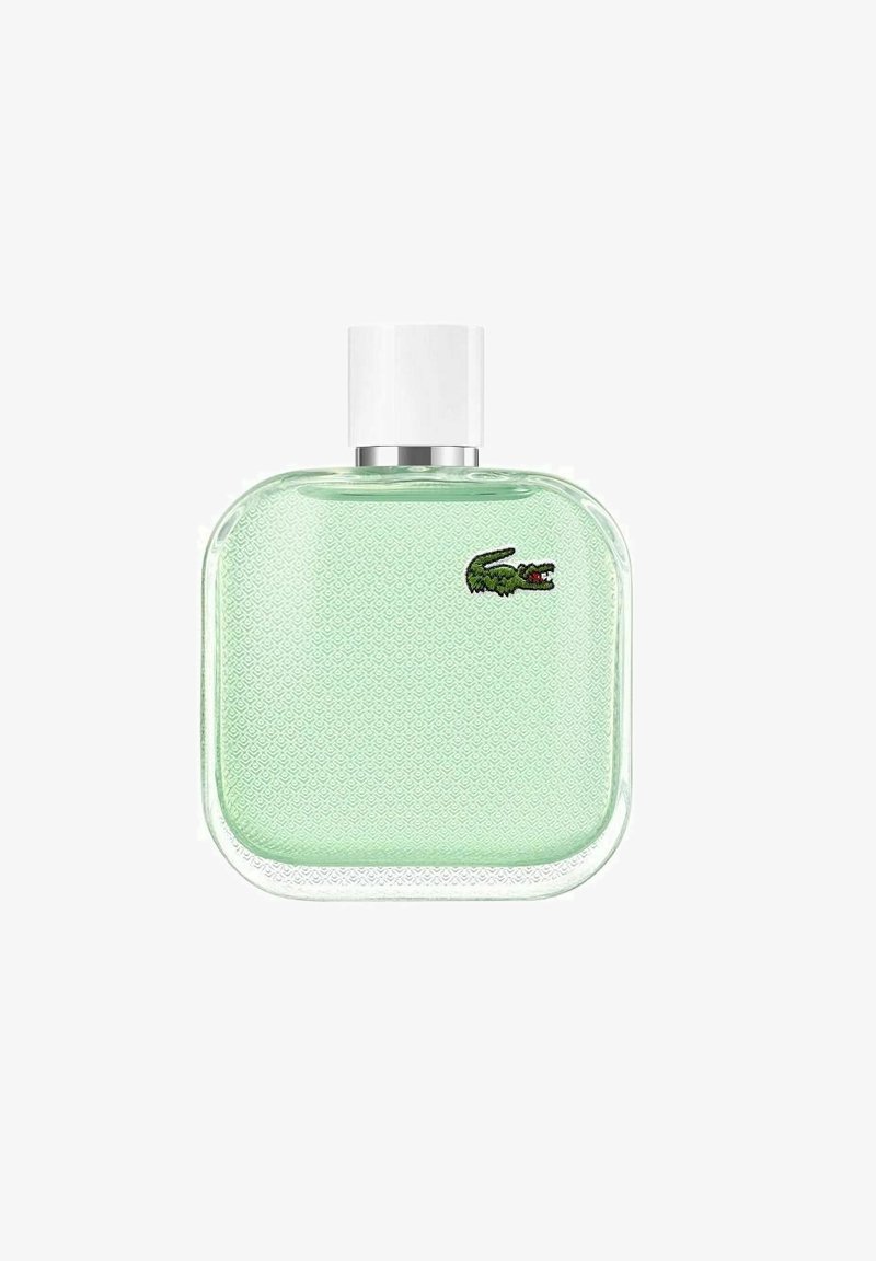 Grön glasparfymflaska med fyrkantig form, texturerad yta, vit kork och en liten broderad krokodil-logotyp.