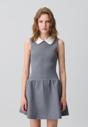 Robe grise avec un corsage ajusté et une jupe évasée. Elle présente un col en dentelle blanc et une texture douce et lisse.