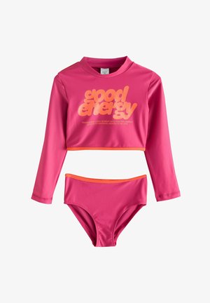 Lyserød bikini sæt med lange ærmer, der har en cropped top med orange detaljer og stor "good energy" tekst, parret med en matchende bund.
