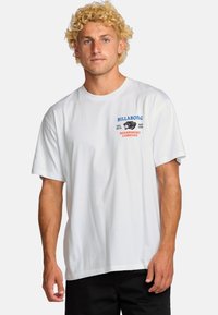 Witte katoenen T-shirt met een grafiek op de borst in blauw en rood met "Billabong" en "Boardshort Company", korte mouwen en ronde hals.