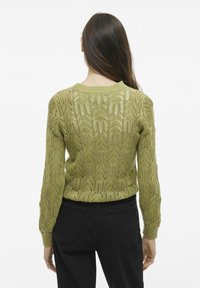 Sweter dzianinowy w oliwkowej zieleni z teksturowanym, otwartym splotem. Posiada ściągacze przy mankietach i u dołu, długie rękawy oraz okrągły dekolt.