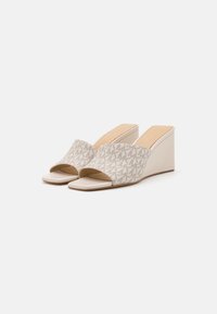 Beige Keilsandalen mit offenem Zeh und einem breiten Riemen, der ein dezentes geometrisches Muster aufweist. Glatte Textur und ein niedriger Absatz.
