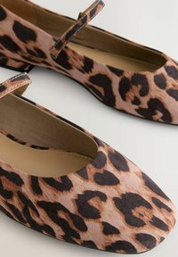 Ballerines à imprimé léopard avec un bout arrondi, tige en tissu doux et une fine sangle traversant le cou-de-pied. Semelle en caoutchouc noire.