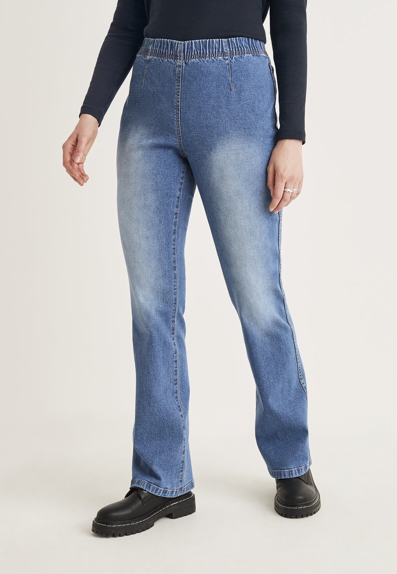 Ljusblå denimjeans med avslappnad passform och elastisk midja, med sidsömmar och subtila blekningar. Bärs med svarta platåboots.