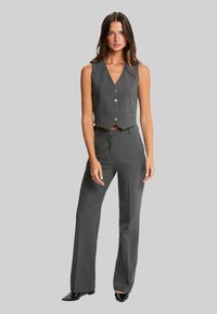 Gilet taillé à rayures grises et pantalon assorti, présentant un design ajusté, cinq boutons et une finition en tissu lisse.