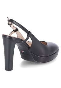 Chaussure à talon haut noire pour femme avec bride à la cheville, bout fermé, semelle plateforme et détail du drapeau italien à l'intérieur.
