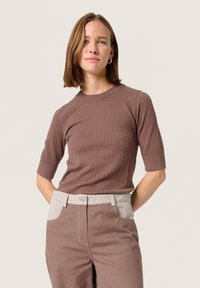 Brown ribbed short-sleeve top with a crew neckline, paired with light brown pants featuring a contrasting light-colored waistband.