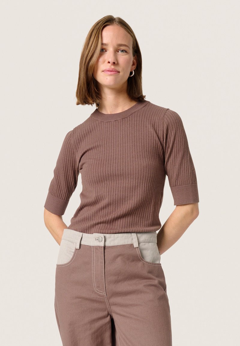 Brown ribbed short-sleeve top with a crew neckline, paired with light brown pants featuring a contrasting light-colored waistband.