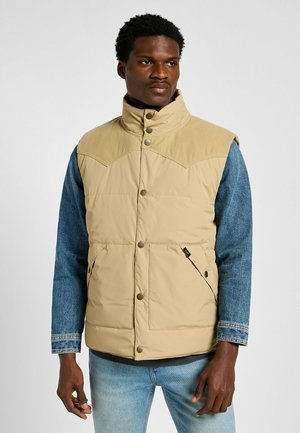 Gilet imbottito color marrone con inserti in corduroy sulle spalle e maniche in denim. Presenta bottoni a pressione e due tasche frontali. Texture liscia su tutta la superficie.
