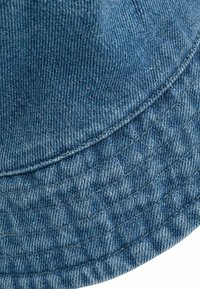 Modrá deninová bucket hat s textúrovanou tkaninou, šitými švami a širokým okrajom. Vzor zobrazuje klasickú tkaninu s keprovým tkaním a rovnomernou farbou.