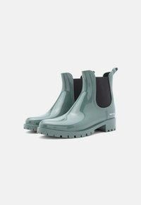 Botas de tornozelo em borracha verde brilhante com painéis laterais elásticos, solas texturizadas e detalhe com logotipo no calcanhar. Design suave e elegante.