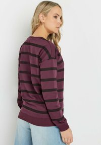 Maglia a maniche lunghe color bordeaux con strisce nere orizzontali, scollatura rotonda, polsini e orlo a coste, e vestibilità comoda. Tessuto morbido in misto cotone.
