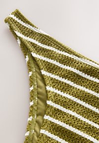 Top bikini verde oliva con design intrecciato e strutturato. Presenta righe bianche orizzontali e fodera liscia. Spalline regolabili.