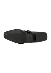 Schwarze Schuhsohle mit einer strukturierten, gemusterten Oberfläche; elegantes Design mit abgerundetem Zehenbereich und flachem Absatz. Minimalistische und robuste Konstruktion.