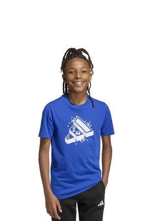 Enfant souriant portant un tee-shirt bleu avec une illustration de console de jeu portable rétro, sur fond blanc.