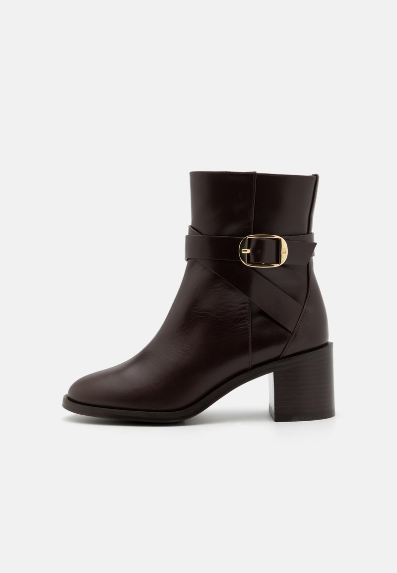 Dark brown leather ankle boot with a rounded toe, wrapped belt detail, gold buckle accent, and a chunky wooden heel.