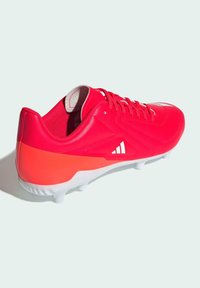 Botas de fútbol rojas con una parte superior sintética suave, suela blanca, acentos texturizados y una sección del talón en contraste naranja. Seis tacos en la suela.