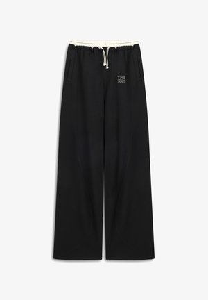 Zwarte sweatpants van zacht materiaal, met een trekkoord in de taille, zijzakken en een geborduurd logo aan de voorkant. Ruimvallend ontwerp.