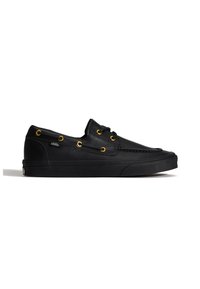 Chaussure bateau Vans en cuir noir avec œillets dorés et semelle en caoutchouc noir, vue de côté sur fond blanc.