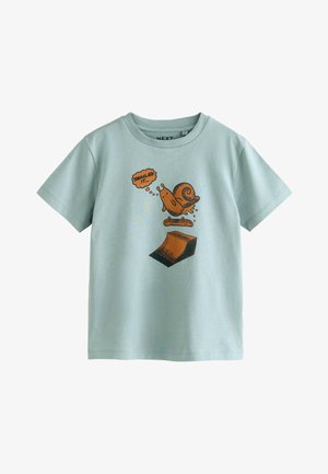 T-shirt en coton bleu clair à manches courtes avec un motif d’escargot brun faisant du skateboard, accompagné d'une bulle de pensée disant "SNAILED IT."