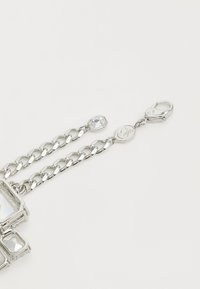 Braccialetto in argento con cristalli chiari rettangolari e ottagonali, dotato di chiusura a gancio e etichetta con logo inciso.