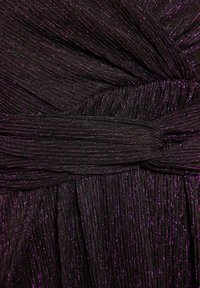 Czarna teksturowana tkanina z fioletowym blaskiem, z fałdami i zawiązanym akcentem na środku. Gładka powierzchnia z błyszczącymi detalami.