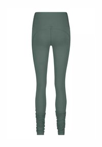 Höga, mörkgröna leggings med rynkade detaljer vid anklarna, visade bakifrån på en vit bakgrund.