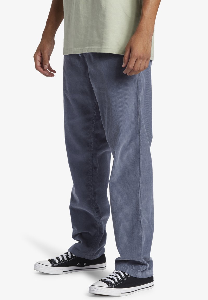 Light blue corduroy pants with a relaxed fit, featuring straight legs and a textured surface. Paired with black low-top sneakers.