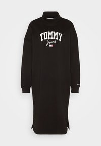 Czarna sukienka sportowa z wysokim dekoltem, długimi rękawami, bocznymi rozcięciami i białym logo "TOMMY Jeans". Wykonana z miękkiego materiału, luźny krój.