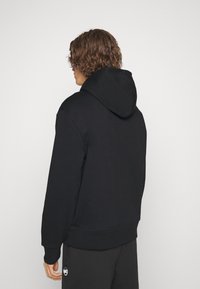 Black hooded sweatshirt with a textured finish, featuring a kangaroo pocket, ribbed cuffs, and hem. View from the back.