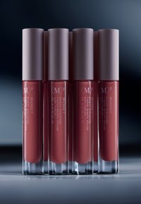 Cinco tubos transparentes de color de labios, cada uno con una tapa mate color malva, que muestran un tono rosa apagado. Las etiquetas incluyen detalles del producto y la marca.