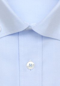 Lichtblauwe overhemdkraag en sliplap met witte knoop, met fijn gestructureerde stof en nette stiknaden.