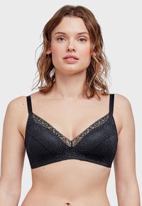 Soutien-gorge noir avec dentelle, présentant une texture florale et un décolleté en V. Les bretelles ajustables et un design sans coutures sont visibles.
