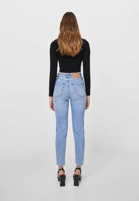 Ljusblå smala jeans med hög midja, klassisk 5-fickdesign och en läderlapp på midjebandet.