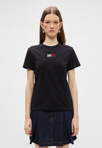 Czarny bawełniany t-shirt z małym haftowanym logo w kolorach czerwonym, białym i niebieskim. Klasyczny okrągły dekolt i krótkie rękawy.