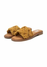 Sandalias planas con base de cuero sintético marrón y parte superior tejida de color amarillo mostaza, que presenta detalles texturizados y un diseño de punta abierta.