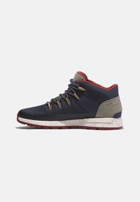 Wysokie sneakersy z siateczkowej cholewki w kolorze granatowym, szarymi akcentami, złotymi oczkami i łuskowatą białą podeszwą z czerwonymi detalami.