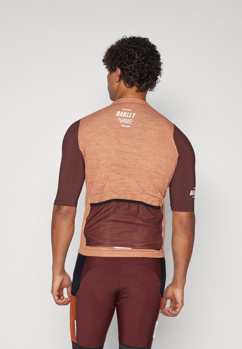 Maglia da ciclismo a maniche corte in arancione bruciato e marrone, con tasca sul retro, tessuto testurizzato e dettagli del logo sulle spalle.