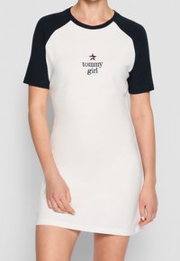 Sukienka z krótkim rękawem z białej bawełny z granatowymi rękawami raglanowymi. Posiada haftowane logo "tommy girl" oraz gwiazdkę nad nim. Gładka tekstura.