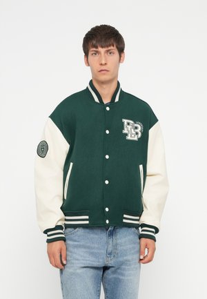 Veste varsity verte et crème avec des fermetures à boutons, des poignets côtelés et un logo sur la poitrine. Équipée de poches latérales et de bords rayés.